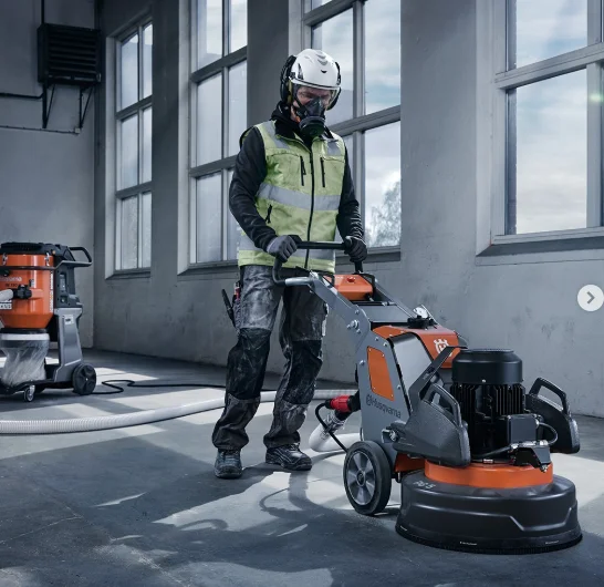 Operario profesional con máquina Husqvarna pulidora de hormigón en acción